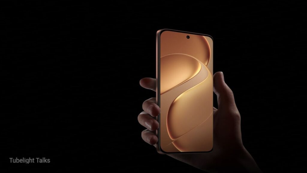 Hand holding a smartphone with a bronze metallic curved wallpaper screen and thin bezels against a dark background.
